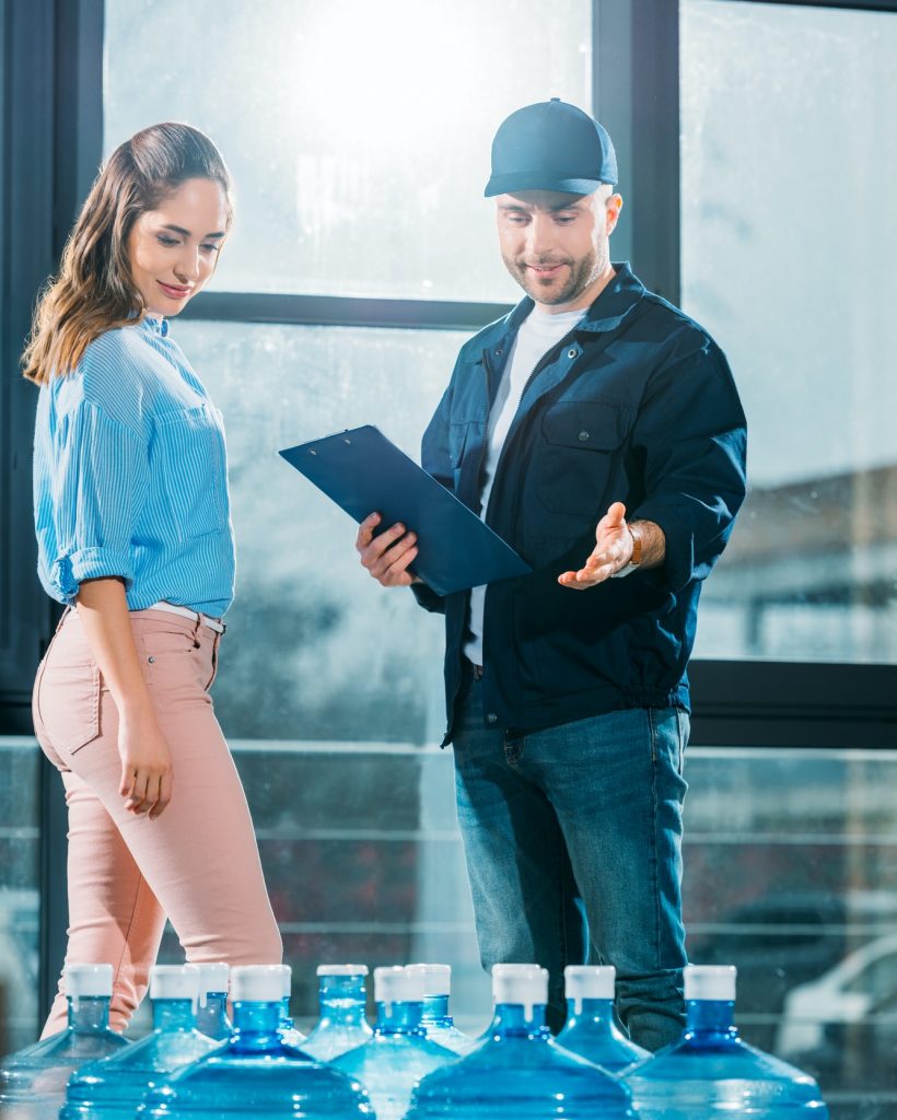 courier-with-clipboard-and-woman-looking-at-delivered-water-bottles.jpg